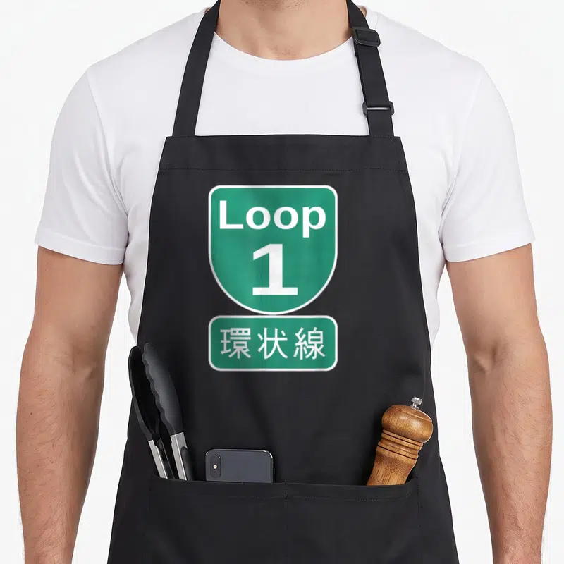 Kanjo design imports vintage apron - Green shield and rectangle signs reading Loop 1 and Japanese characters — shown on a black cotton canvas apron against a white background