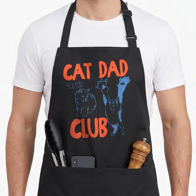 Funny better cat apron - Orange CAT DAD CLUB text with two blue line-art cats and script — shown on a black cotton canvas apron against a white background