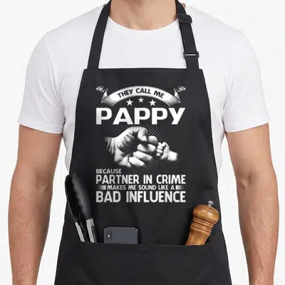 Pappy girl they apron - White text ribbon and three stars above PAPPY and hands doing a fist bump — shown on a black cotton canvas apron against a white background