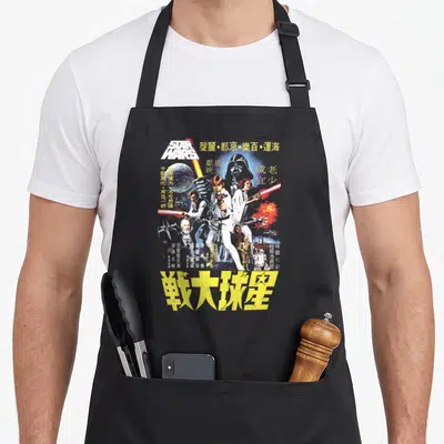 Movie chinese apron - Retro Star Wars poster art with Chinese characters and yellow title text — shown on a black cotton canvas apron against a white background