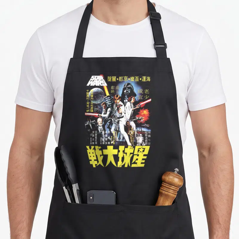 Movie chinese apron - Retro Star Wars poster art with Chinese characters and yellow title text — shown on a black cotton canvas apron against a white background