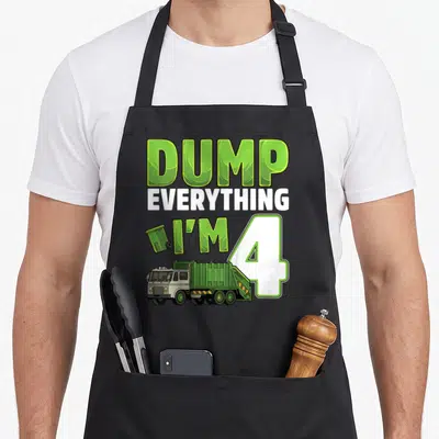 Garbage 4th truck apron - Green and white DUMP EVERYTHING I'M 4 text with cartoon truck and trash can — shown on a black cotton canvas apron against a white background