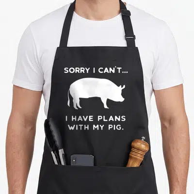 Outfit farmer apron - White pig silhouette between text Sorry I Can't I Have Plans With My Pig — shown on a black cotton canvas apron against a white background