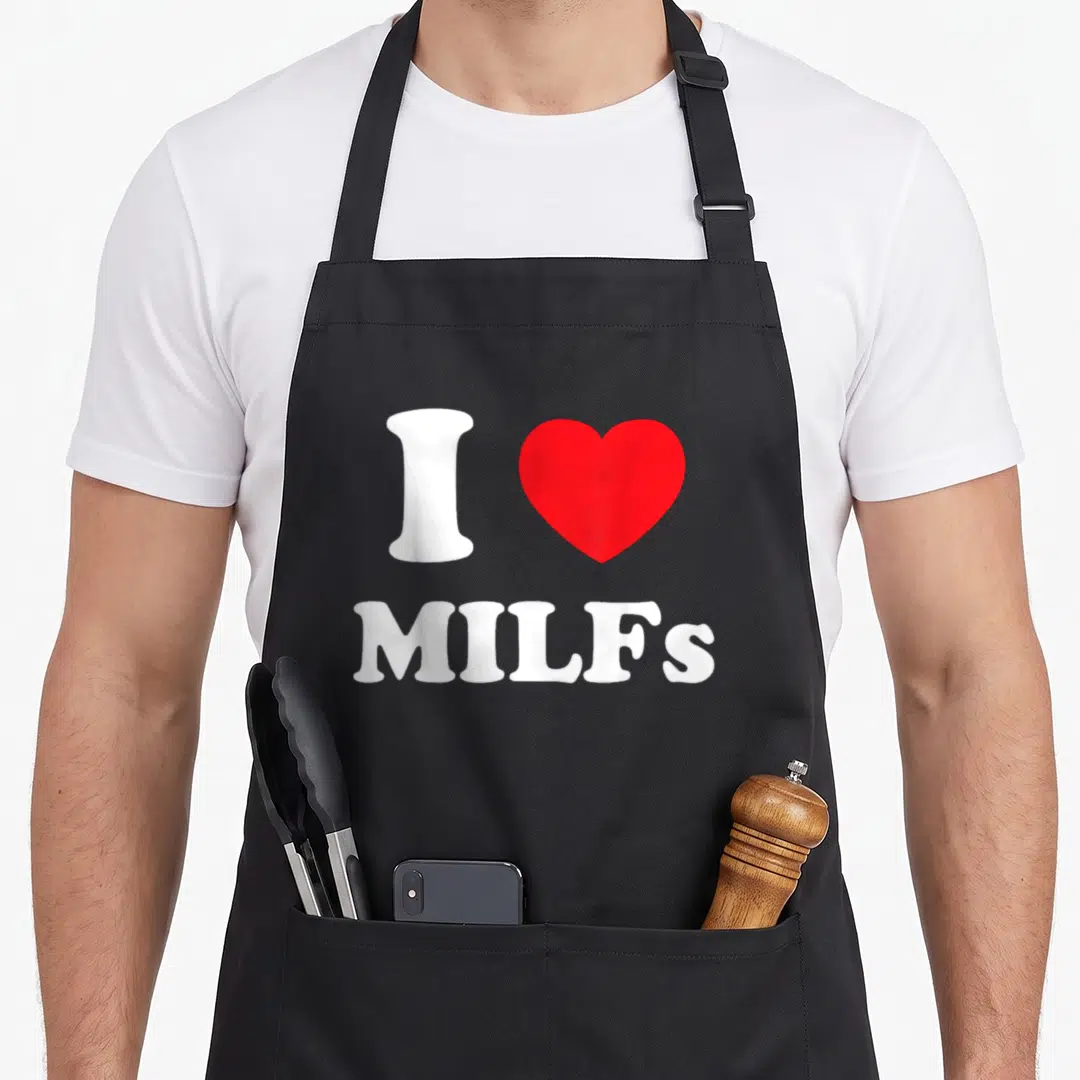 Mature milf apron - White I next to red heart above centered white MILFs text — shown on a black cotton canvas apron against a white background