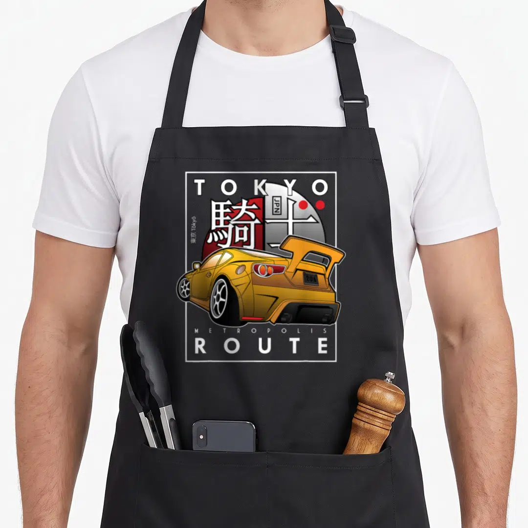 Tokyo design imports vintage apron - Yellow modified car with Tokyo Metropolis Route text and red sun background — shown on a black cotton canvas apron against a white background