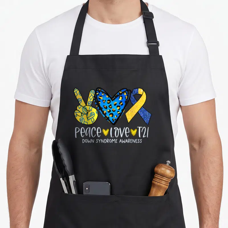 Support down syndrome awareness apron - Peace sign, leopard heart, and ribbon with text PEACE LOVE T21 and DOWN — shown on a black cotton canvas apron against a white background