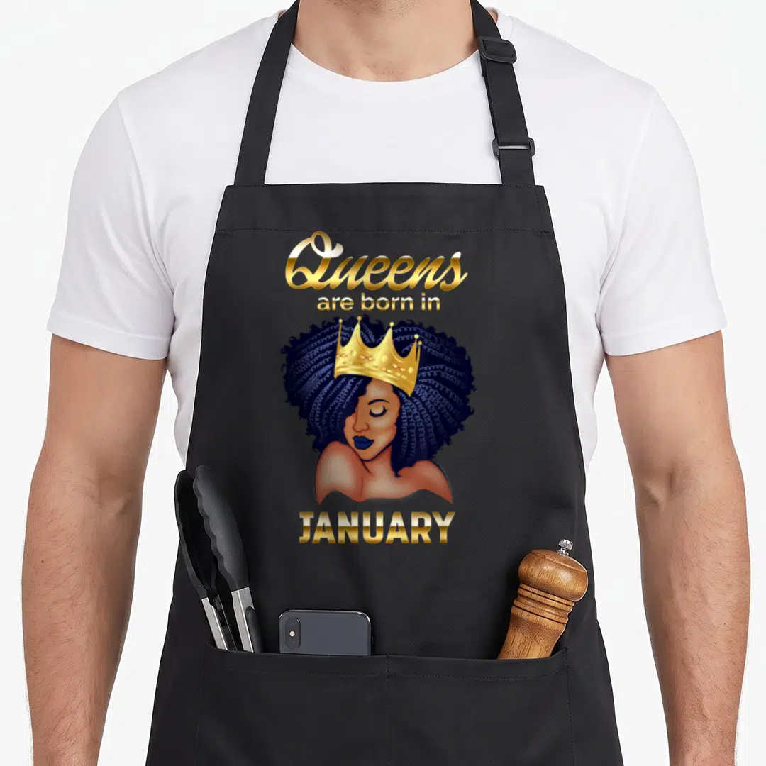 Vintage january birthday apron - Crowned woman illustration with gold text Queens are born in JANUARY on a black bib — shown on a black cotton canvas apron against a white background
