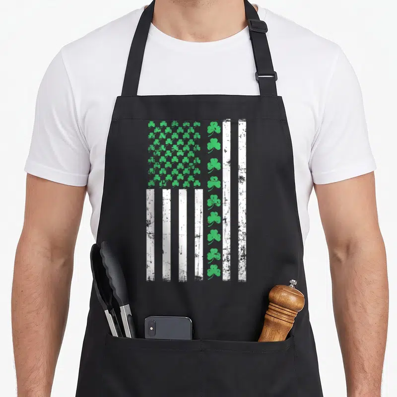 Flag st patrick day aprons - Stylized flag with green shamrock grid and distressed white grey stripes — shown on a black cotton canvas apron against a white background