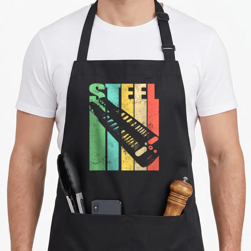 Lap classic rock apron - Retro STEEL text over green teal yellow red grey stripes with diagonal grey boot silhouette — shown on a black cotton canvas apron against a white background