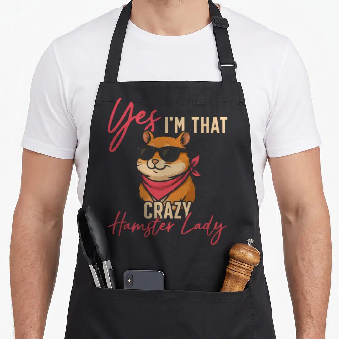 Animal crazy hamster lady apron - Cartoon hamster with sunglasses and red bandana surrounded by Yes I'm That Crazy — shown on a black cotton canvas apron against a white background