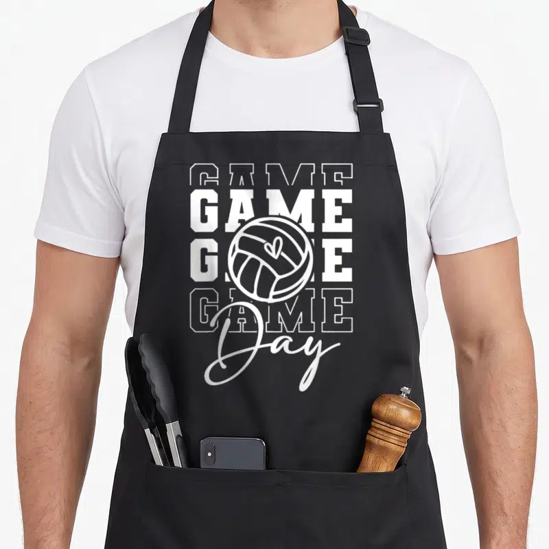 Volleyball game aprons - White stacked GAME text with volleyball containing a heart and script Day below — shown on a black cotton canvas apron against a white background
