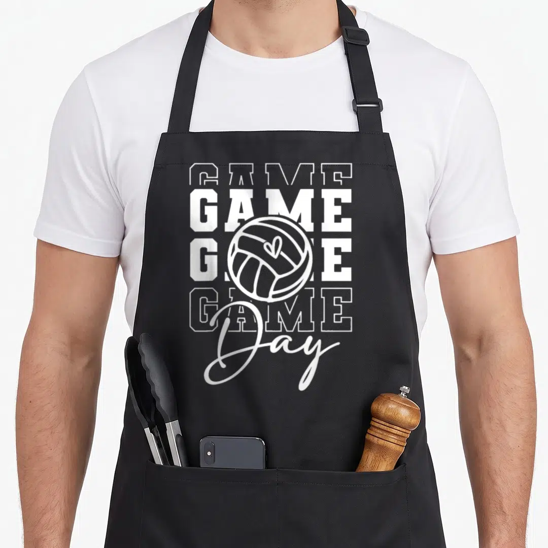 Volleyball game aprons - White stacked GAME text with volleyball containing a heart and script Day below — shown on a black cotton canvas apron against a white background