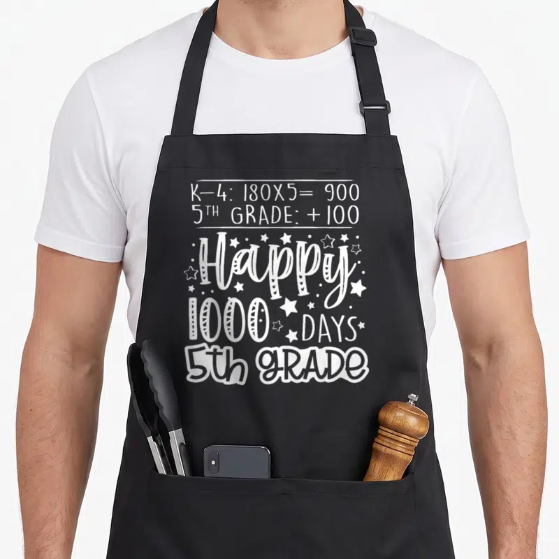 Smarter fifth grade teacher apron - White 1000 Days math text and stars celebrating 5th grade school milestone — shown on a black cotton canvas apron against a white background