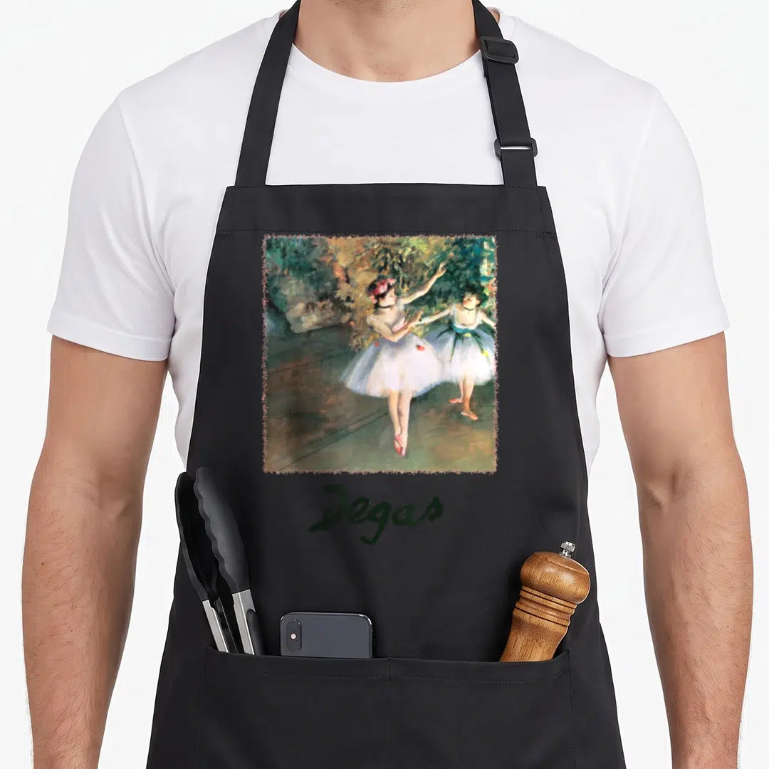 Stage ballerina apron - Square print of two ballerinas in green and white with Degas text below — shown on a black cotton canvas apron against a white background