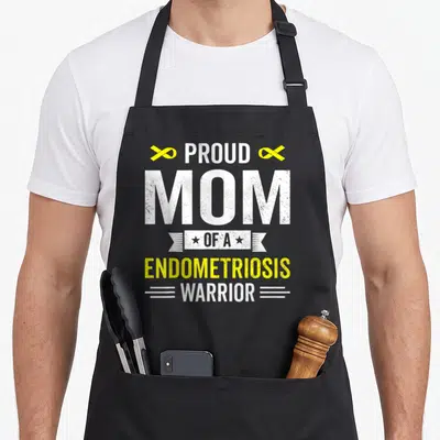 Proud endometriosis awareness apron - Stacked text PROUD MOM OF A ENDOMETRIOSIS WARRIOR with yellow ribbons and white — shown on a black cotton canvas apron against a white background