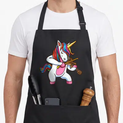 Geiger unicorn apron - Cartoon white unicorn with rainbow mane standing and playing a brown violin — shown on a black cotton canvas apron against a white background