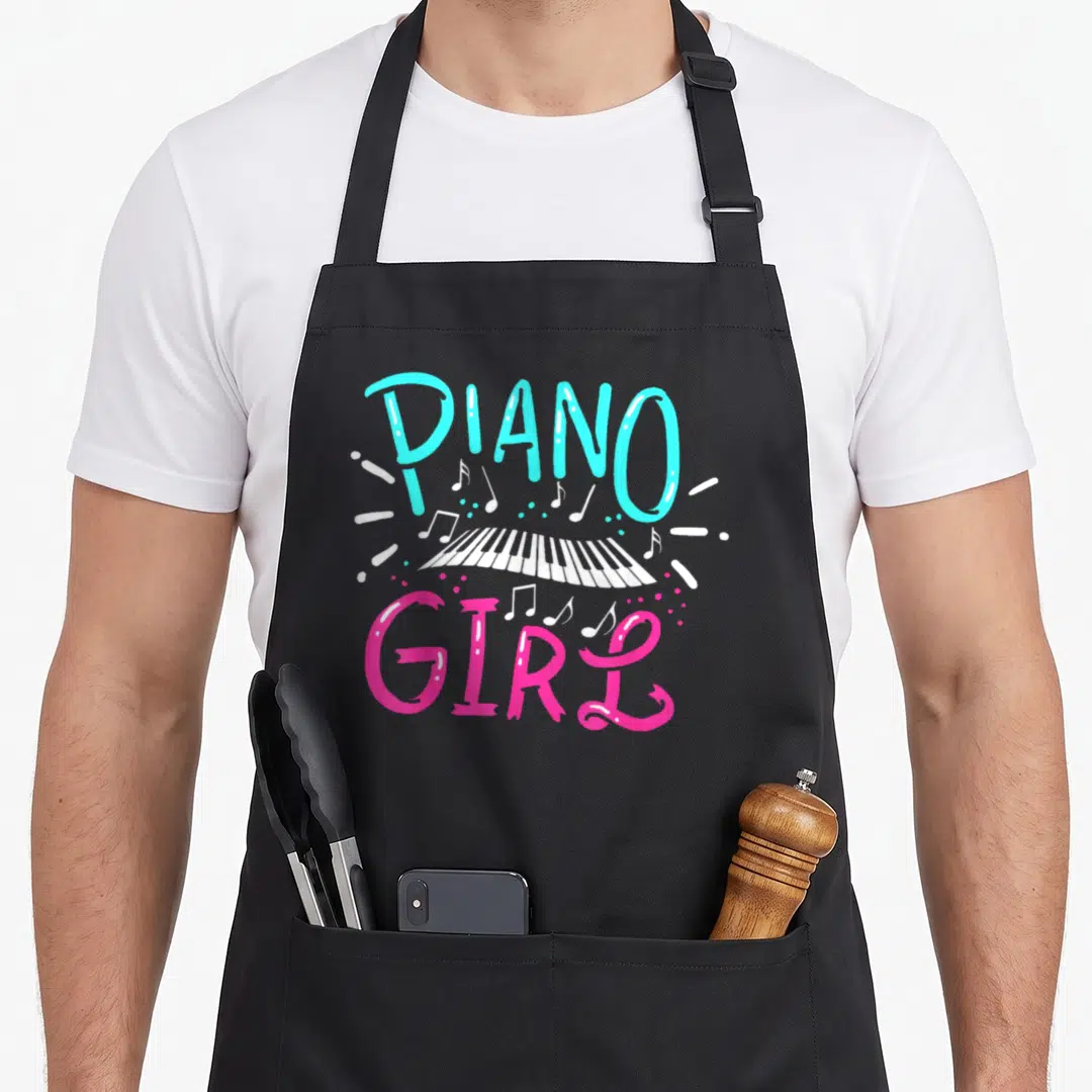 Pianist music note piano apron - PIANO GIRL text in cyan and pink surrounding a white piano keyboard with musical notes — shown on a black cotton canvas apron against a white background