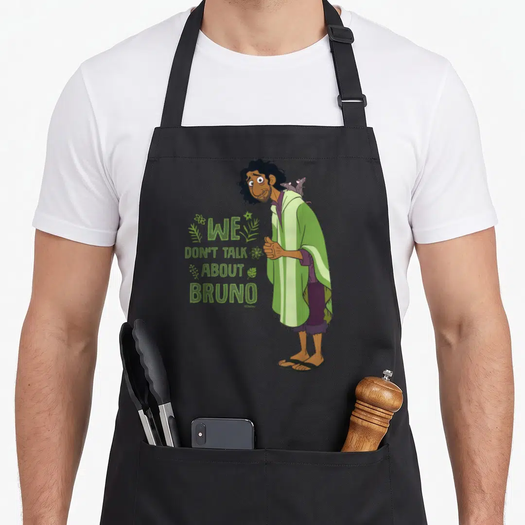 Talk vintage bruno apron - We Don't Talk About Bruno text with cartoon man and rats in green and purple — shown on a black cotton canvas apron against a white background