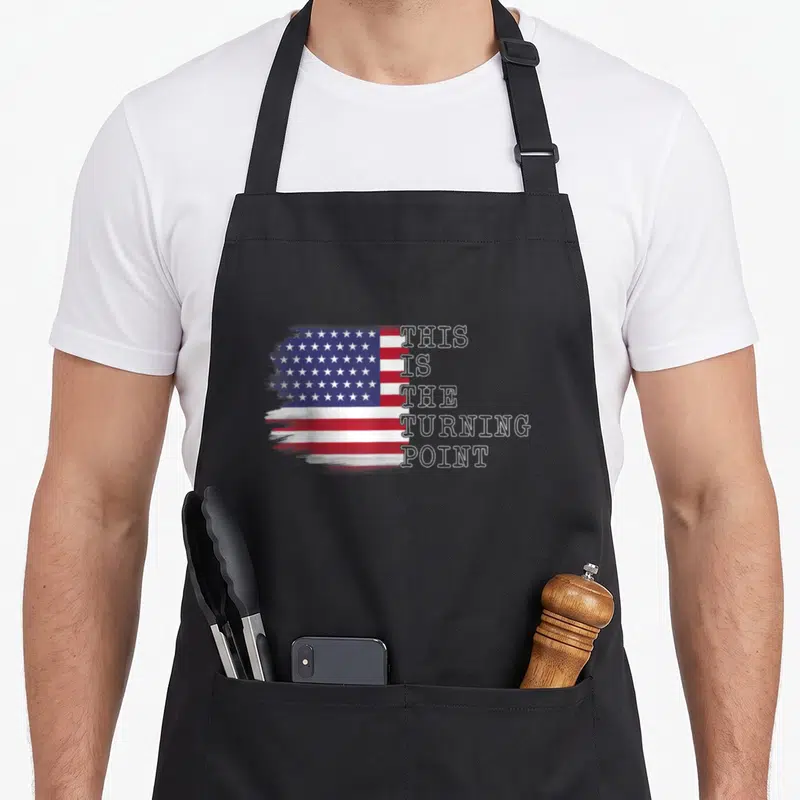 Point turning apron - Distressed USA flag with stacked outline text THIS IS THE TURNING POINT in red white blue — shown on a black cotton canvas apron against a white background