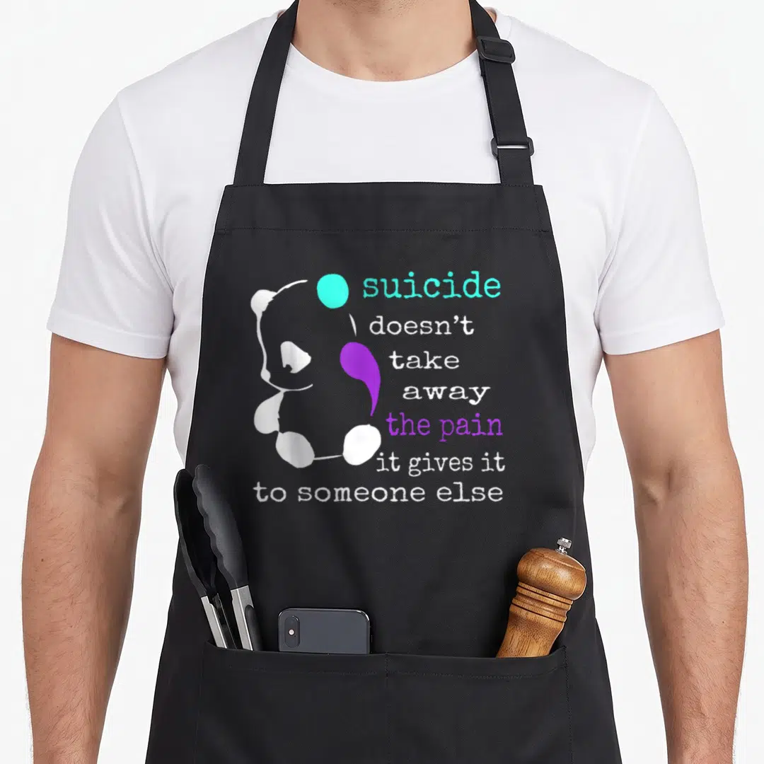 Suicide depression awareness apron - White panda graphic with cyan circle and purple semicolon shape next to stacked — shown on a black cotton canvas apron against a white background