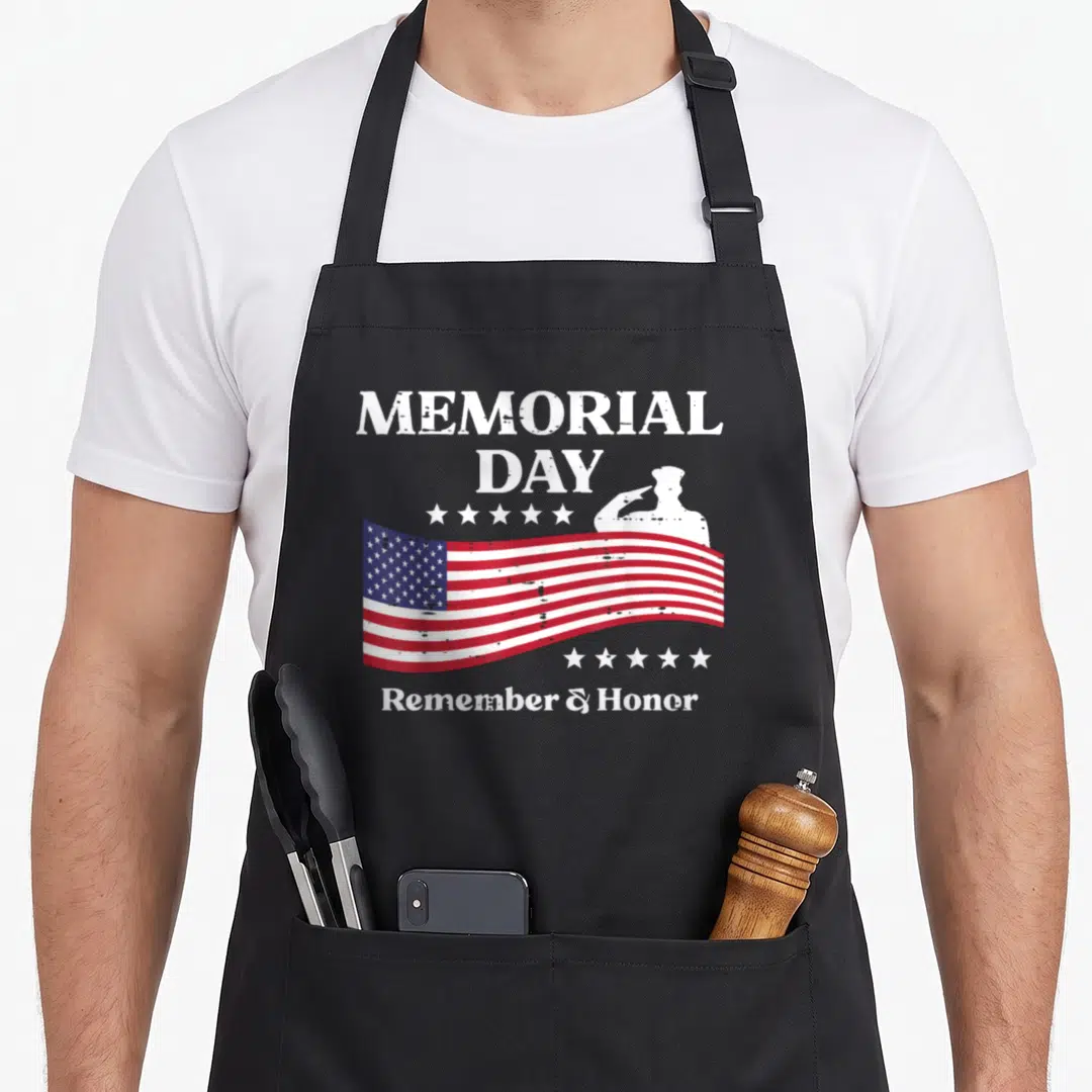 Memorial patriots apron - Distressed USA flag with saluting soldier silhouette and MEMORIAL DAY text surrounded by stars — shown on a black cotton canvas apron against a white background