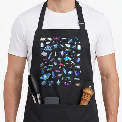 Bug lot of aprons - Cartoon beetles, butterflies, dragonflies, and spiders in blue, purple, and white on black fabric — shown on a black cotton canvas apron against a white background