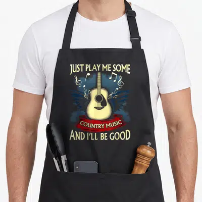 Play cook's country aprons - Acoustic guitar with blue wings and country music text on black bib — shown on a black cotton canvas apron against a white background