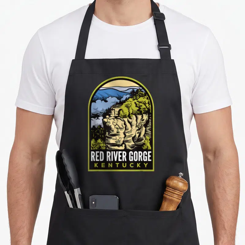 River chimney apron - Retro arched print of beige rock formation and green trees with Red River Gorge Kentucky text — shown on a black cotton canvas apron against a white background