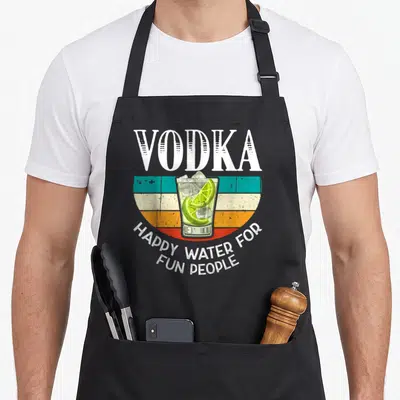 Water vodka apron - Retro vodka glass with lime and ice over teal, orange, and white stripes with white text — shown on a black cotton canvas apron against a white background