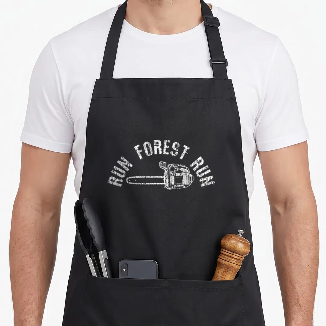 Lumberjack wood apron - White distressed chainsaw with RUN FOREST RUN text in a circular arch — shown on a black cotton canvas apron against a white background
