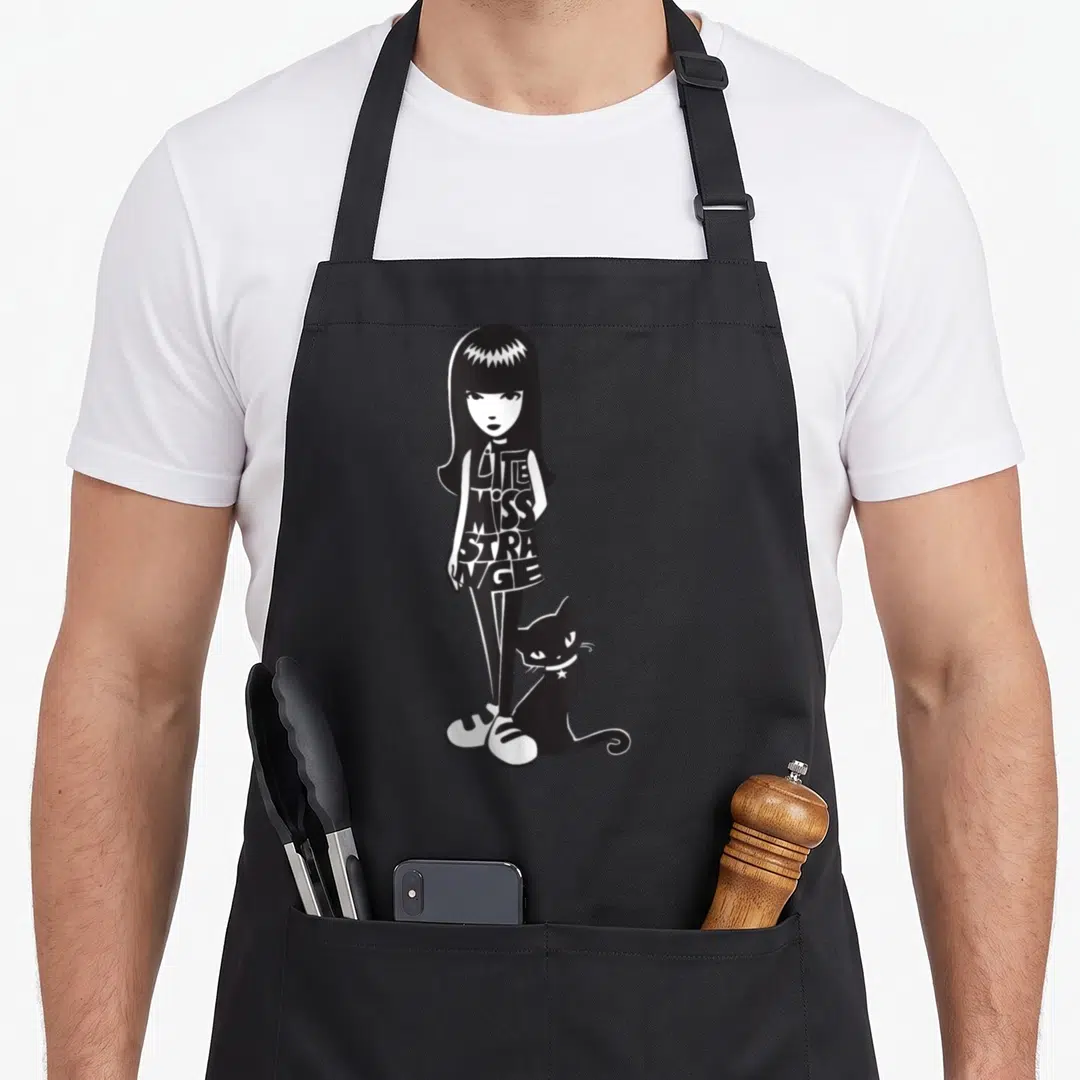 Miss mississippi girl apron - Stylized girl with bob hair and black cat, LITTLE MISS STRANGE text on dress — shown on a black cotton canvas apron against a white background