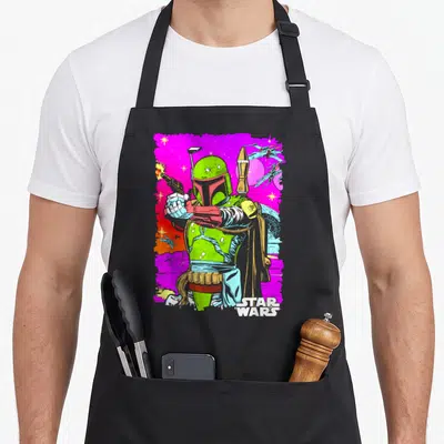 Vibrant black nerd apron - Boba Fett cartoon figure on magenta space background with STAR WARS logo — shown on a black cotton canvas apron against a white background