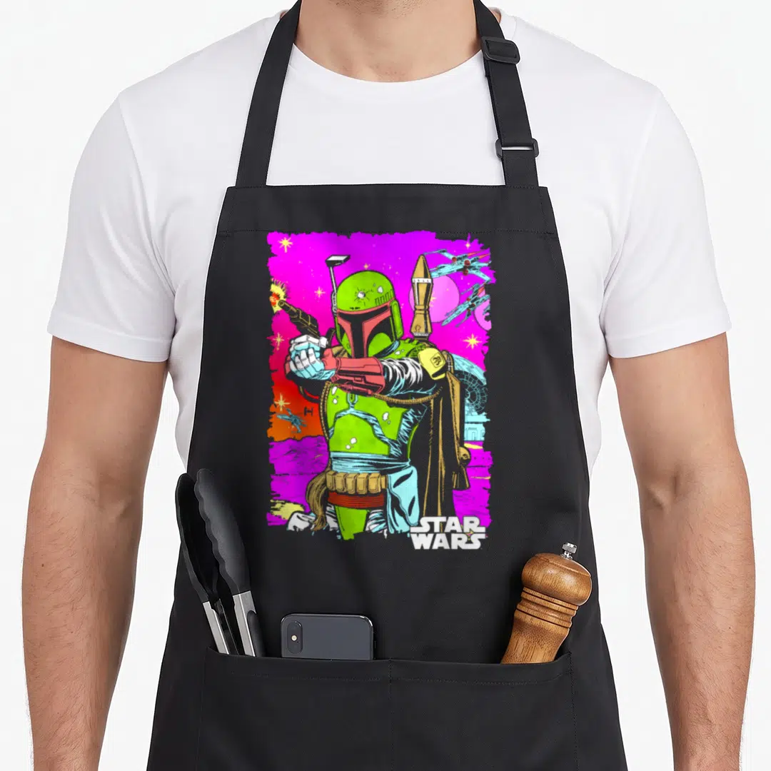 Vibrant black nerd apron - Boba Fett cartoon figure on magenta space background with STAR WARS logo — shown on a black cotton canvas apron against a white background
