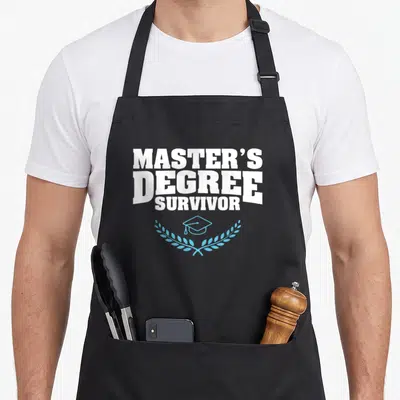Mba student master apron - White stacked text reading Master's Degree Survivor above a blue cap and laurel wreath — shown on a black cotton canvas apron against a white background