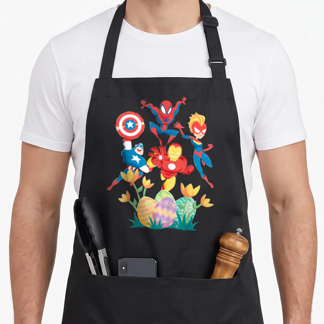 Funny hunt easter egg apron - Four superheroes leaping above decorated eggs and yellow tulips in red, blue, yellow — shown on a black cotton canvas apron against a white background
