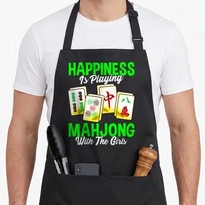 Tile mahjong apron - Four mahjong tiles with green and red markings under green and white text reading Happiness Is — shown on a black cotton canvas apron against a white background