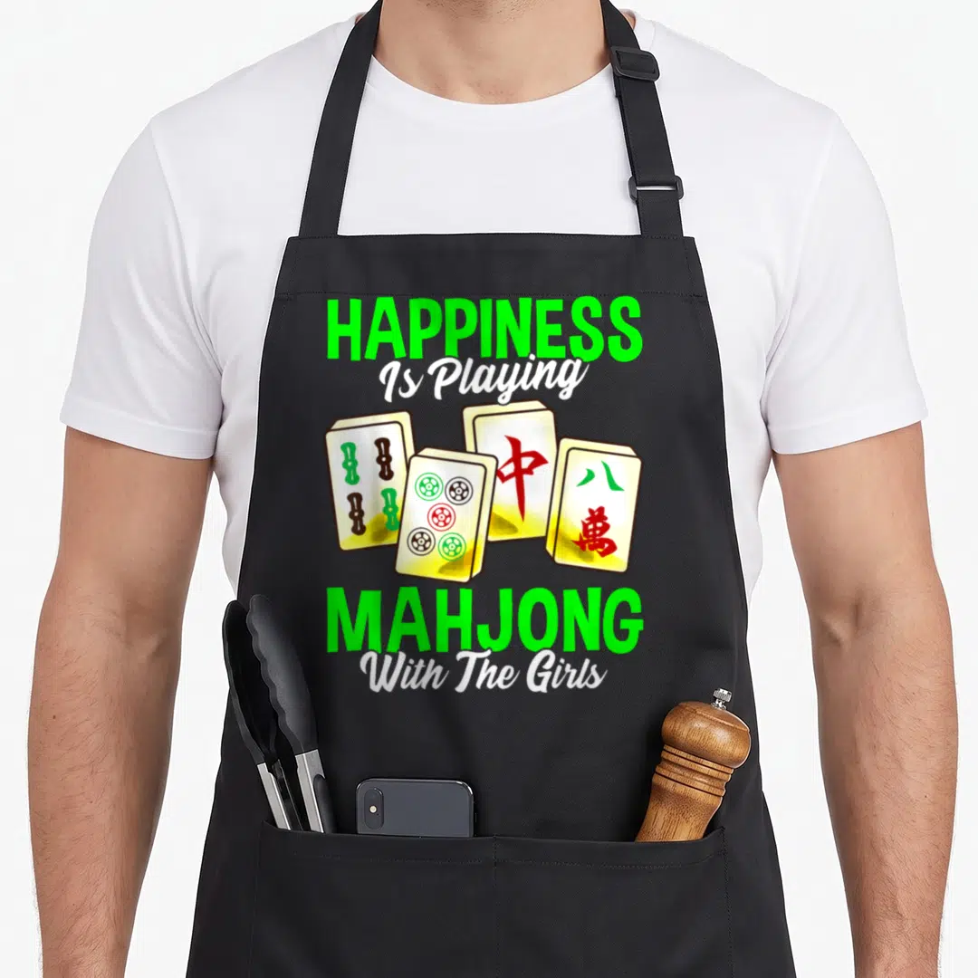 Tile mahjong apron - Four mahjong tiles with green and red markings under green and white text reading Happiness Is — shown on a black cotton canvas apron against a white background