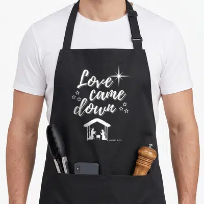 Came womens christmas apron - White Love came down text and nativity scene on black apron — shown on a black cotton canvas apron against a white background