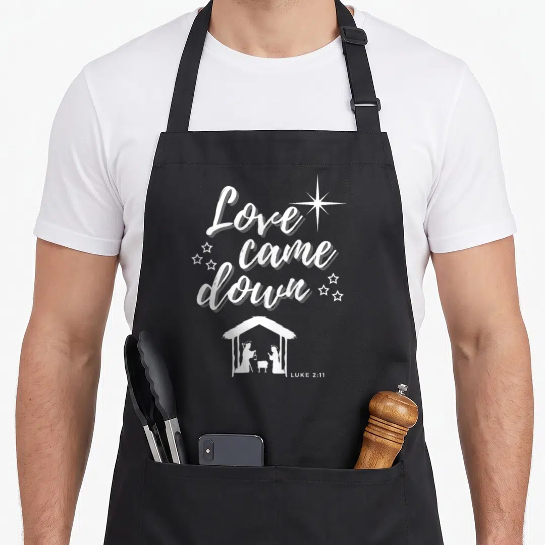 Came womens christmas apron - White Love came down text and nativity scene on black apron — shown on a black cotton canvas apron against a white background