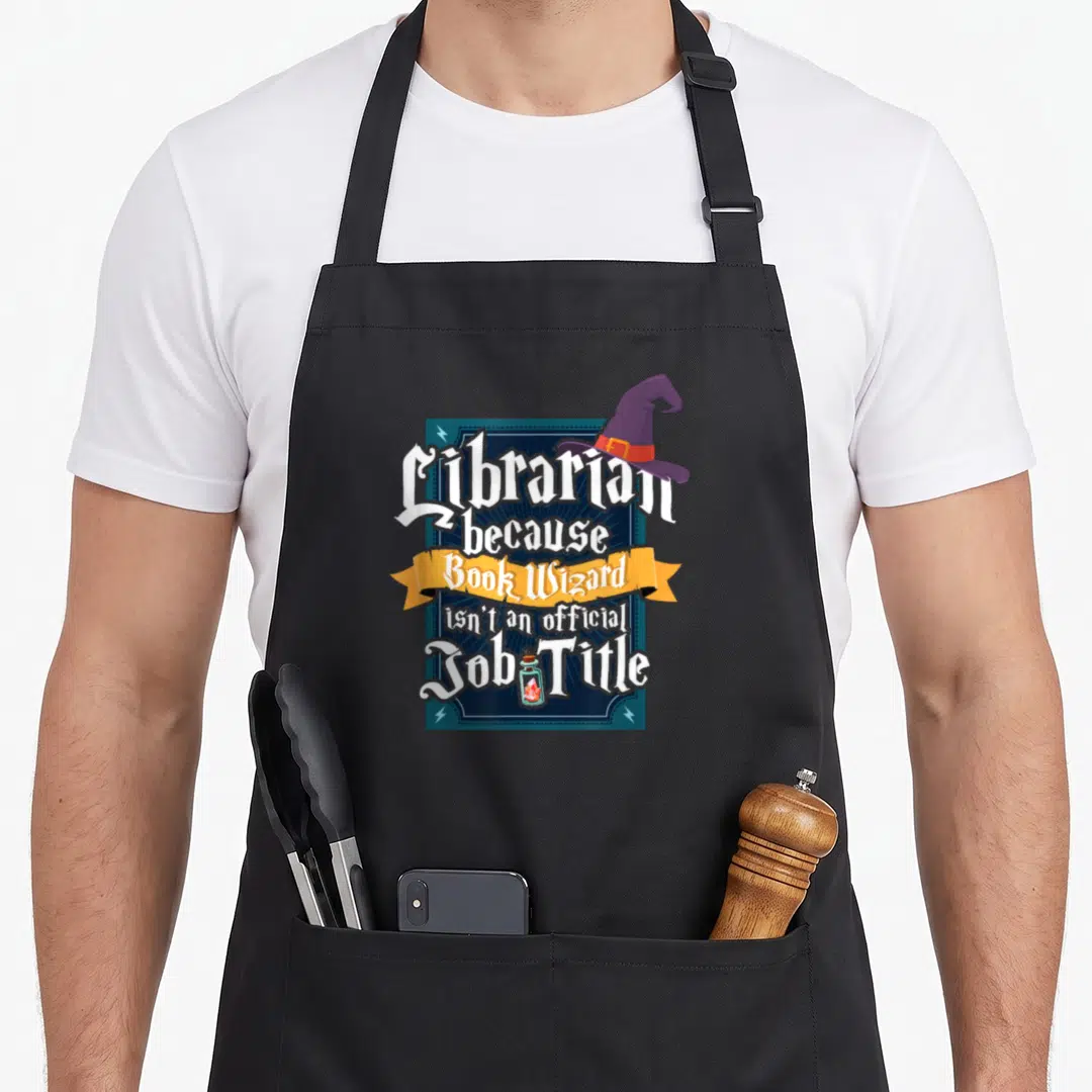 Book reading lover apron - Librarian text with purple witch hat, yellow banner, and potion bottle on blue frame — shown on a black cotton canvas apron against a white background