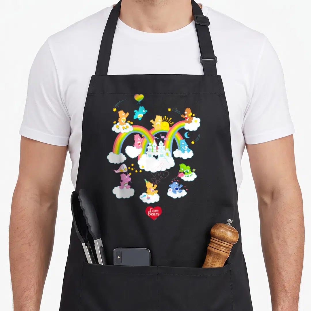 Cloud bear apron - Care Bears on clouds with rainbow, castle, sun, moon, red heart logo — shown on a black cotton canvas apron against a white background