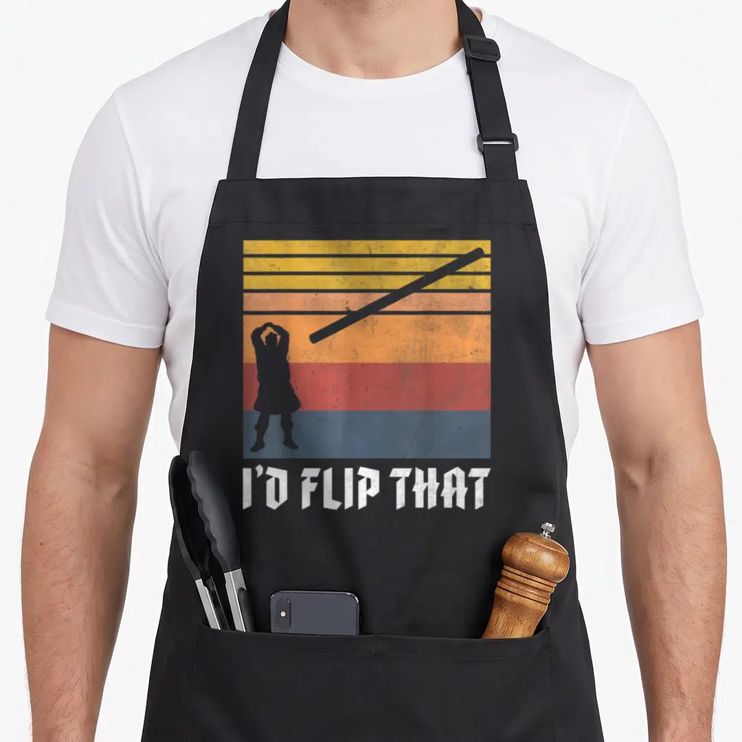 Toss kilt apron - Retro striped silhouette of person tossing pole with text I'D FLIP THAT — shown on a black cotton canvas apron against a white background