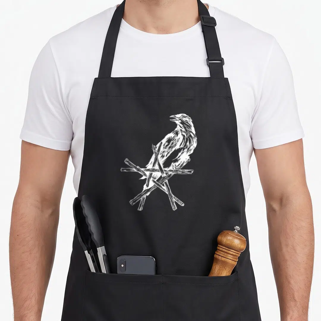 Star ravens apron - White line-art crow perched on crossed branches, no text or symbols — shown on a black cotton canvas apron against a white background