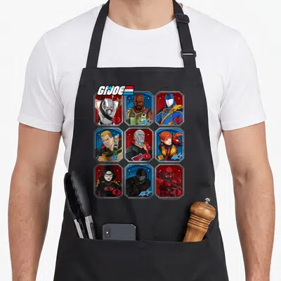 Joe box apron - GI JOE logo above nine character portraits in hex frames with red blue white grey backgrounds and small — shown on a black cotton canvas apron against a white background
