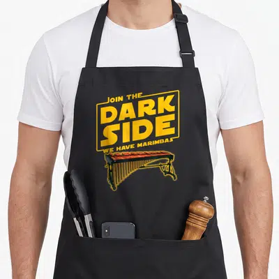 Join marimba apron - Yellow text box reading Join The Dark Side We Have Marimbas above a marimba instrument — shown on a black cotton canvas apron against a white background