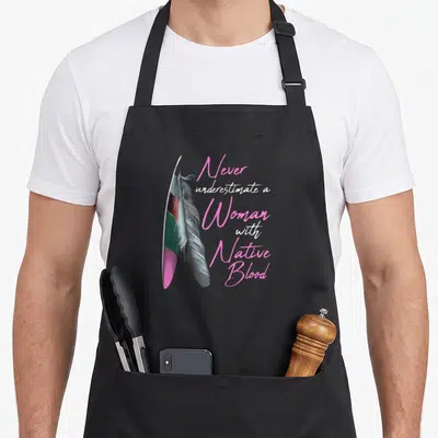 Funny blood apron - Two vertical feathers in pink, white, grey, and green next to stacked script text — shown on a black cotton canvas apron against a white background