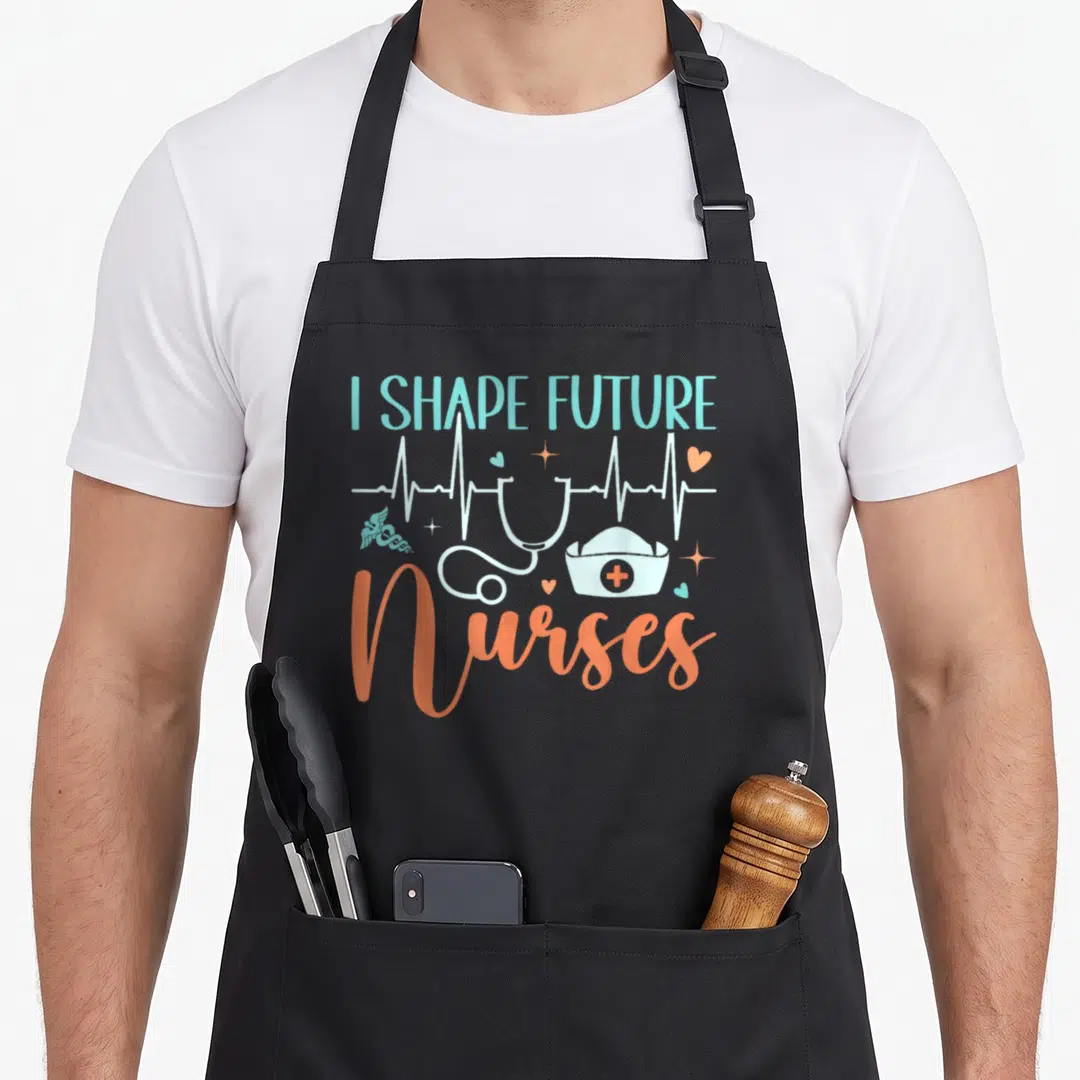 Shape nurse apron - I SHAPE FUTURE Nurses stethoscope nurse hat cartoon print — shown on a black cotton canvas apron against a white background