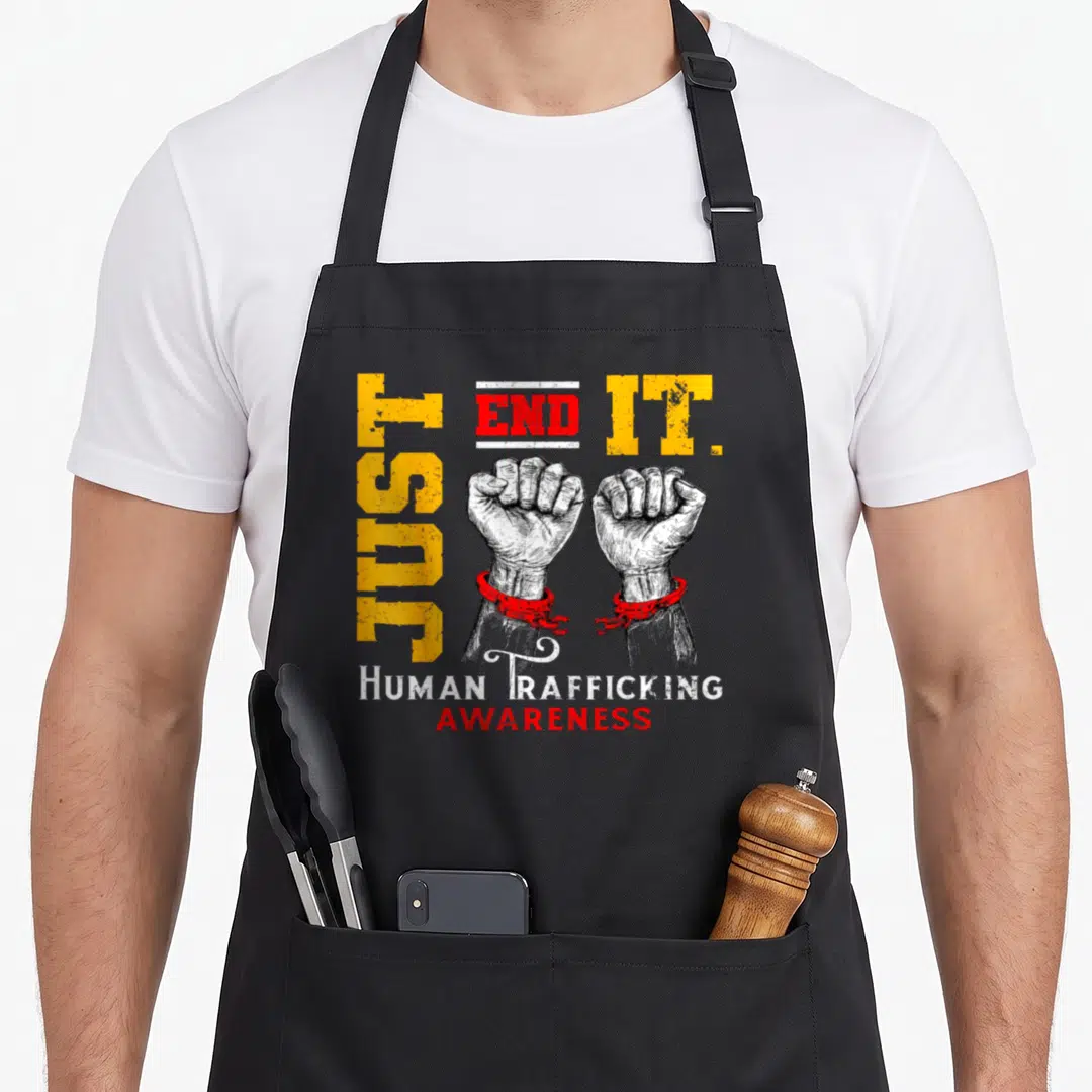 End modern apron - Two white fists in red handcuffs with vertical Just End It text — shown on a black cotton canvas apron against a white background