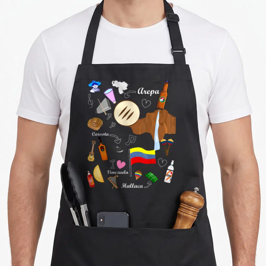 Proud venezuelan apron - Collage of arepa, hallaca, flag, and labeled Venezuelan cultural symbols in cartoon style — shown on a black cotton canvas apron against a white background