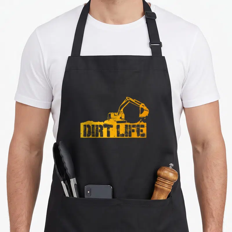 Dirt heavy canvas aprons - Orange excavator on dirt pile with distressed DIRT LIFE text — shown on a black cotton canvas apron against a white background